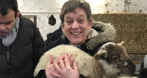 Isabelle, résidente au SRA, tient un agneau dans ses bras